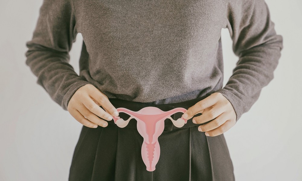 Frau haltet sich Cutout von einem Uterus vor ihren Unterleib 